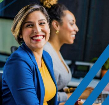 Two smiling women in front of laptops